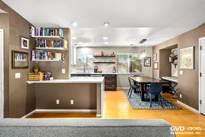 Modern kitchen remodel featuring dark cabinetry, open shelving, and a dining area with a blue rug
