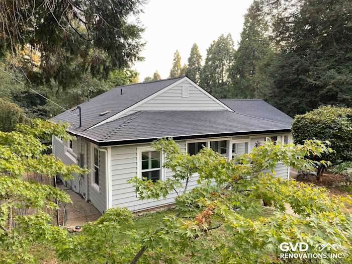 Updated home exterior featuring Prodigy Vinyl Siding in light gray, surrounded by lush greenery in Grass Valley