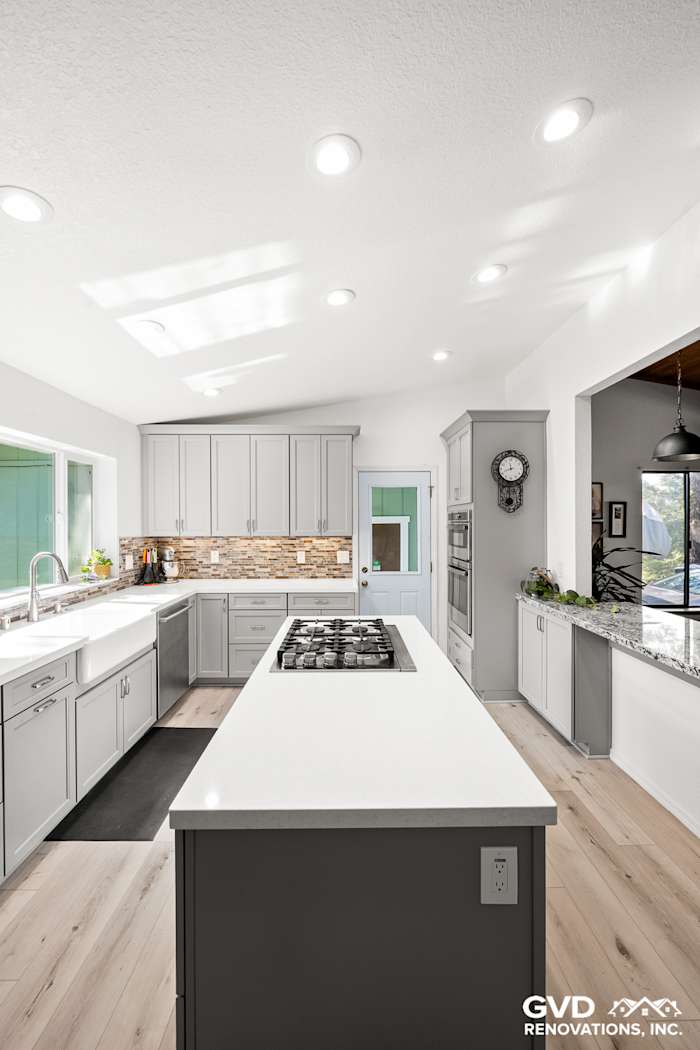 Modern kitchen remodel in Greenwood featuring gray cabinetry, quartz countertops, and a spacious island with a cooktop