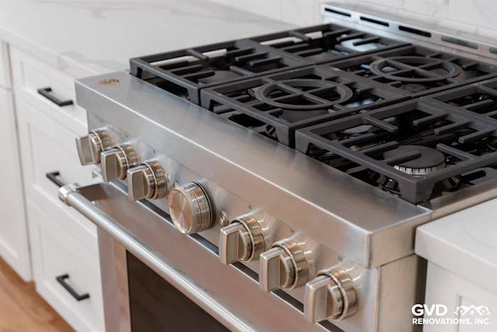 Close-up of a stainless steel gas range with five burners in a custom kitchen design