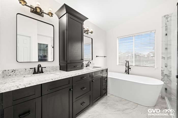 Modern bathroom with a double sink vanity, black cabinetry, freestanding tub, and large windows