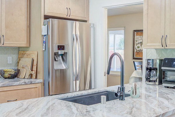 Modern kitchen remodel featuring light wood cabinets, quartz countertops, stainless steel appliances, and a kitchen island