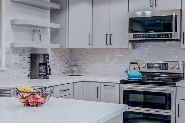 Modern kitchen remodel with gray cabinetry, white quartz countertops, and patterned backsplash in Sacramento
