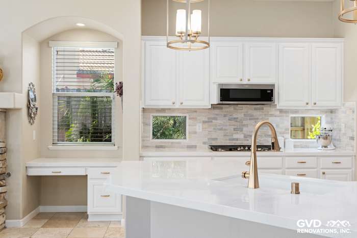 Modern kitchen with white cabinets, quartz countertop, and backsplash, featuring a window view and stylish lighting fixtures
