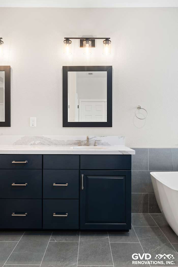 Modern master bathroom with navy cabinetry, marble countertop, and stylish wall sconces in El Dorado Hills
