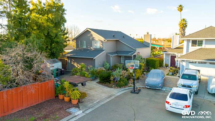 Updated home exterior featuring Alside Prodigy Vinyl siding in Ageless Slate, with landscaped yard and cars in driveway