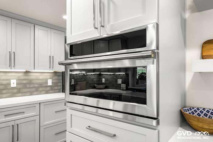Modern kitchen remodel in Rocklin showcasing stainless steel microwave and sleek gray cabinetry with white countertops