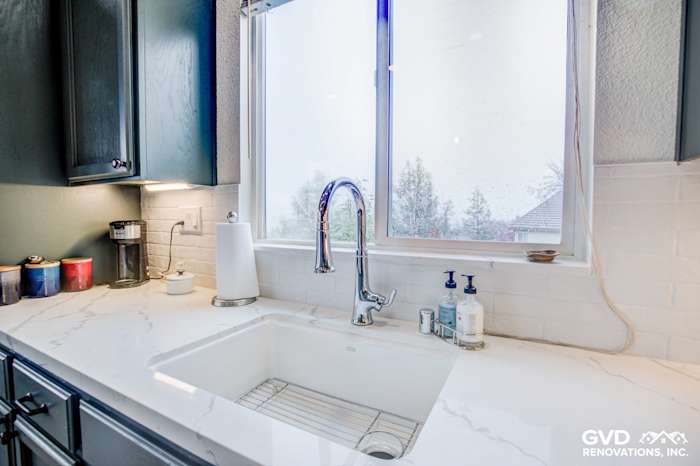Bright kitchen sink area featuring a large farmhouse sink, marble countertop, and stylish faucet