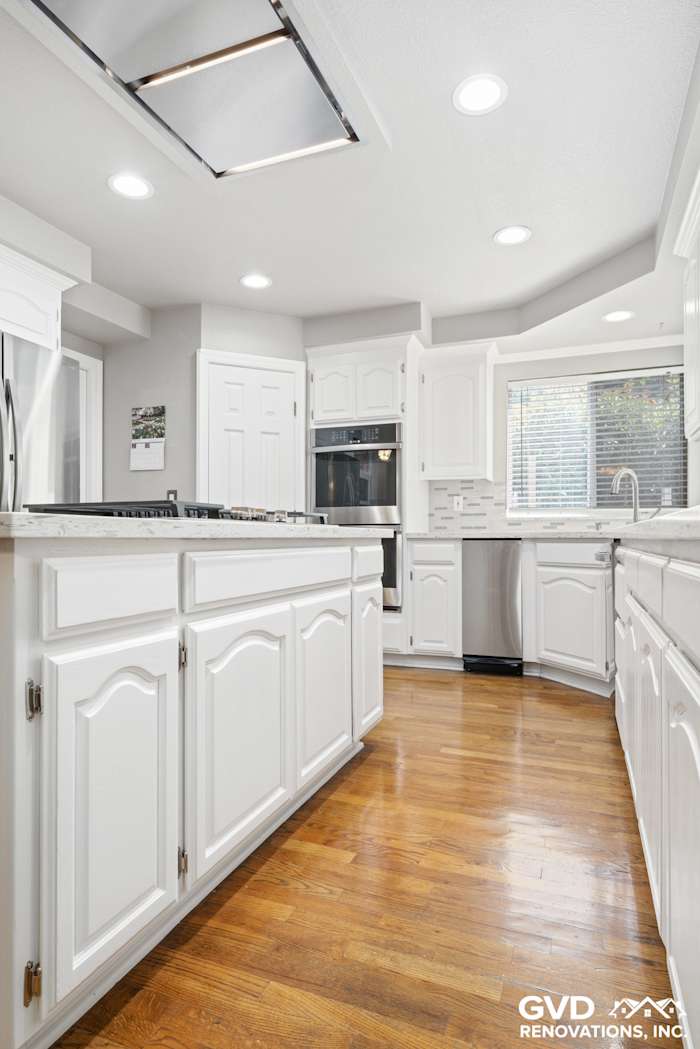 Bright Fair Oaks kitchen renovation featuring white cabinetry and wood flooring, with stainless steel appliances
