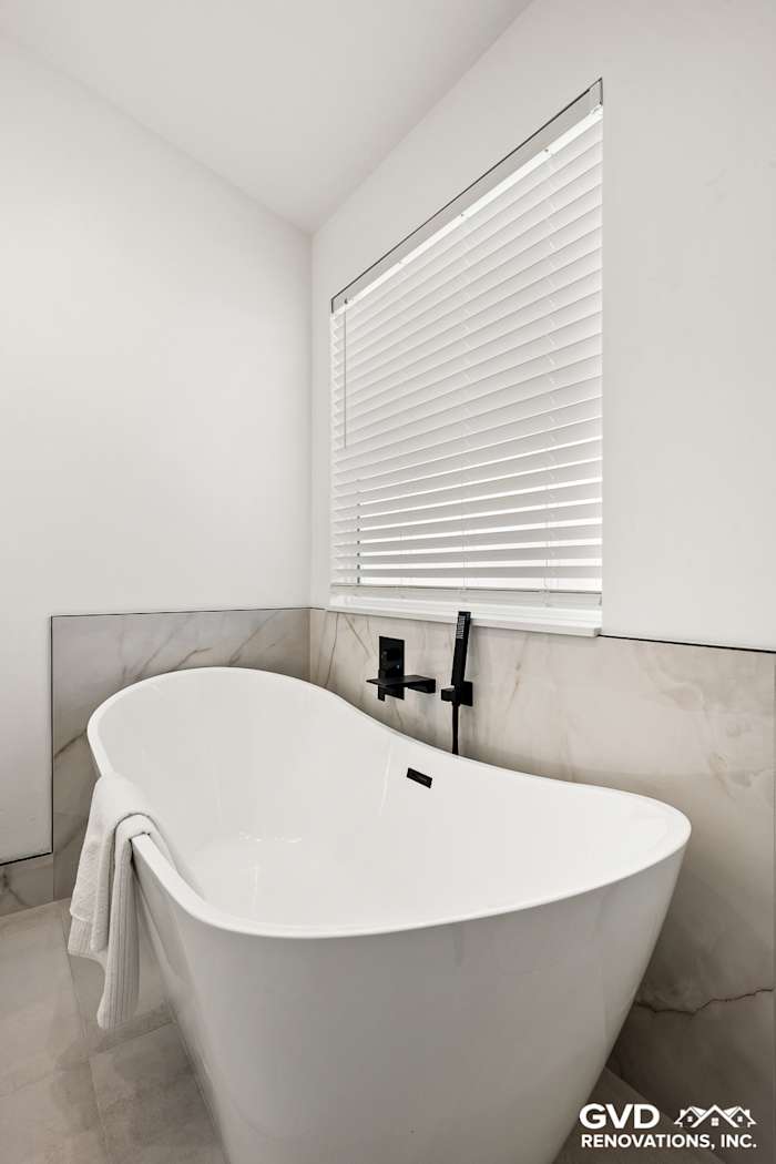 Freestanding white tub with sleek black fixtures and modern tile, enhancing the bathroom remodel in Antelope, CA