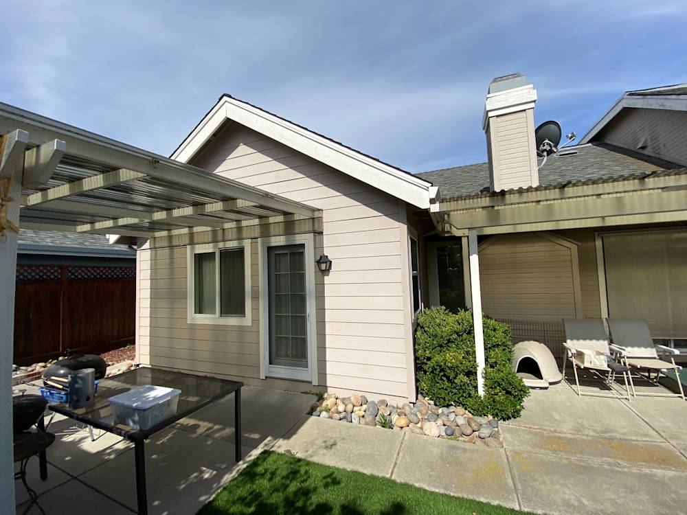Side view of a single-story home in Sacramento with light-colored siding and a concrete patio
