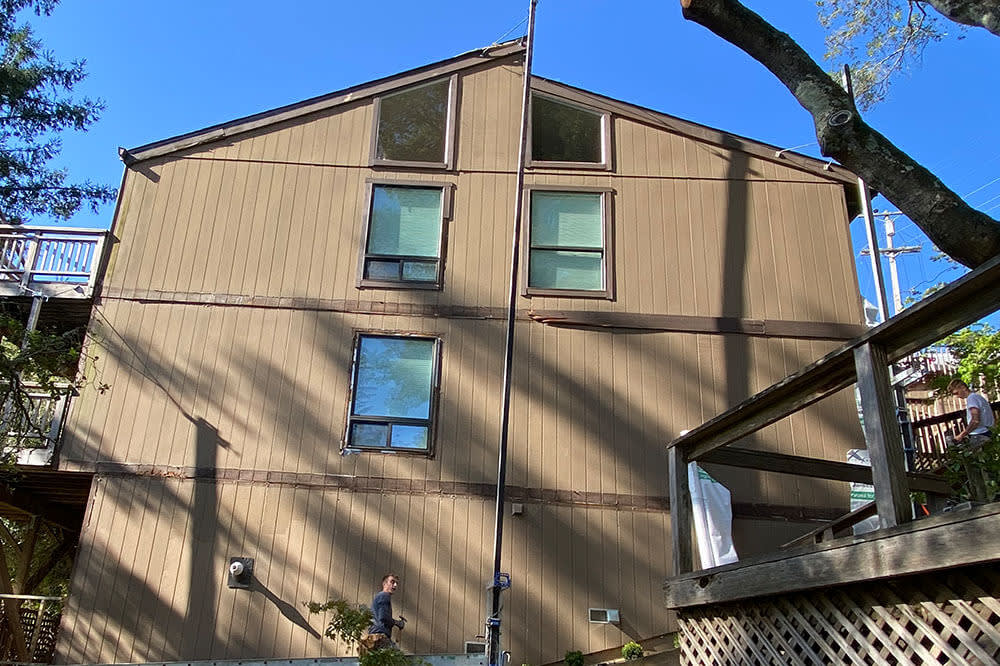 Two-story brown siding home in Novato, with large windows and wooden deck features