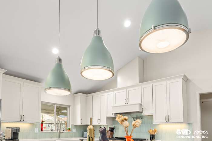 Modern kitchen in Carmichael featuring custom white cabinetry, mint green pendant lights, and a stylish backsplash
