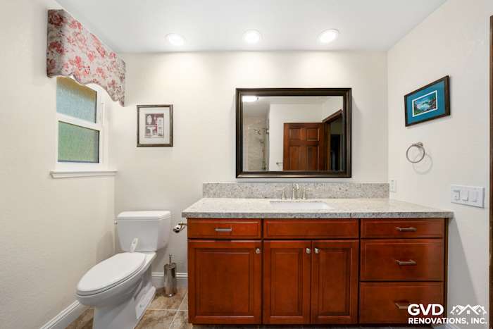 Bright bathroom with granite countertop, dark wood cabinetry, and modern fixtures in Fair Oaks