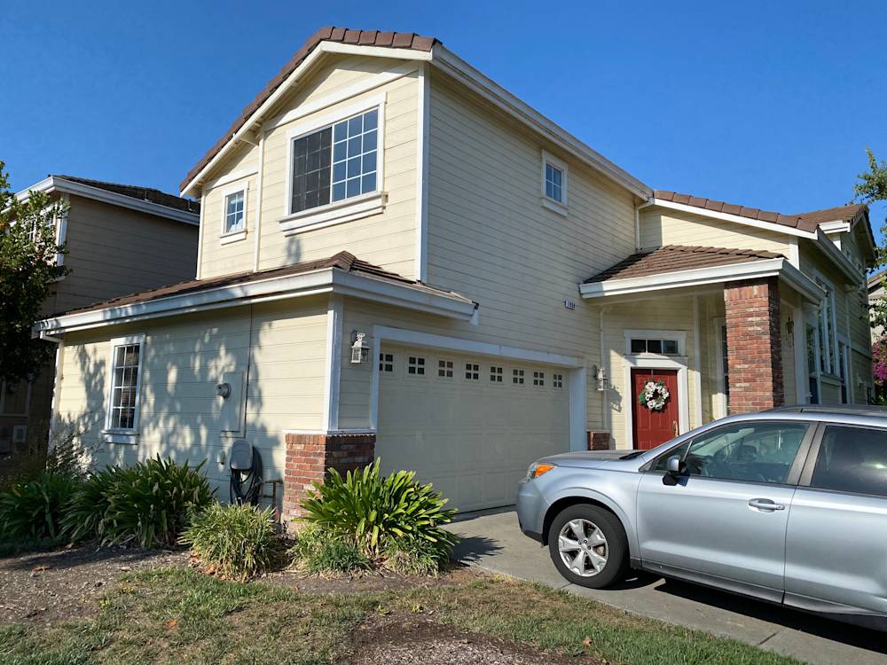Dated yellow siding home in Sacramento, featuring a brick accent and garage
