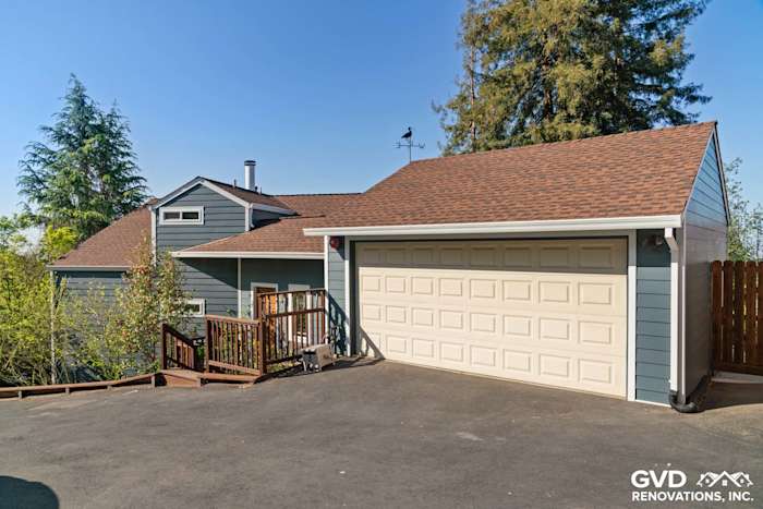 Modern home exterior featuring blue James Hardie lap siding, new windows, and a two-car garage in Oakland