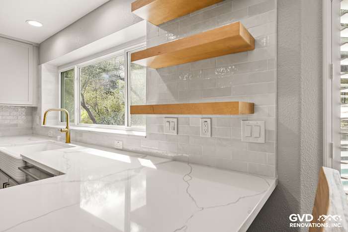 Luxurious quartz countertop with white subway tile backsplash and wooden open shelves in modern kitchen remodel