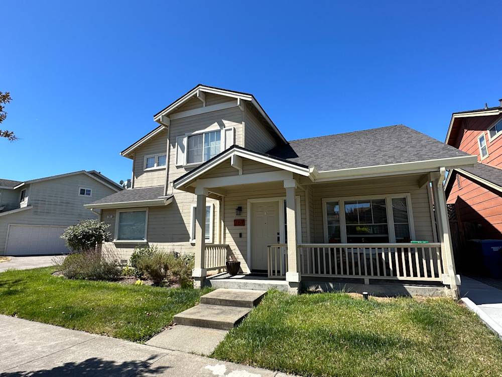 Two-story home with beige siding, welcoming porch, and green lawn in Sacramento