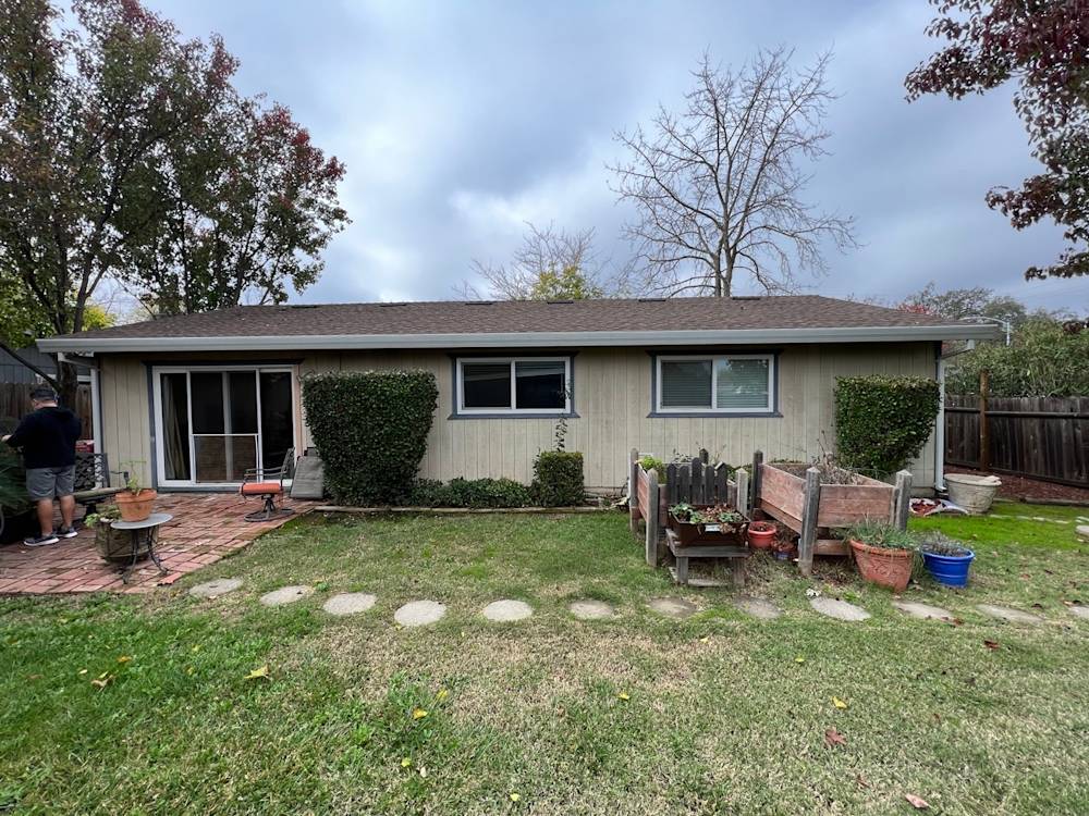 Single-story home exterior with beige siding, brown roof, landscaped yard and patio in Sacramento area