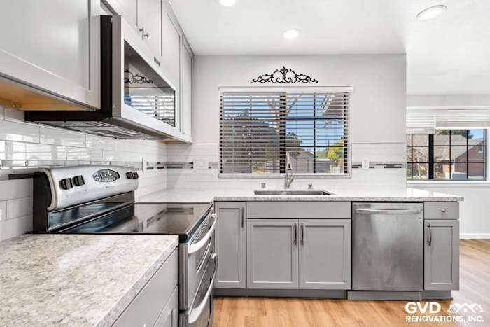 Modern kitchen with gray cabinets, granite countertops, stainless steel appliances, and large window in Carmichael, CA