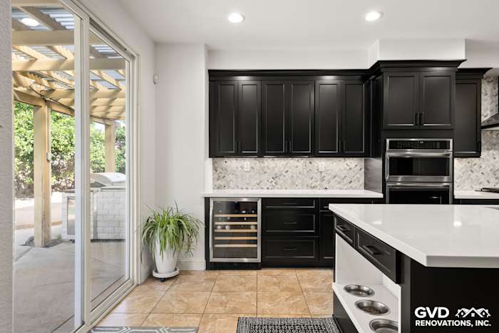 Modern kitchen in Roseville featuring black Waypoint cabinets, MSI countertops, and a built-in pet feeding station