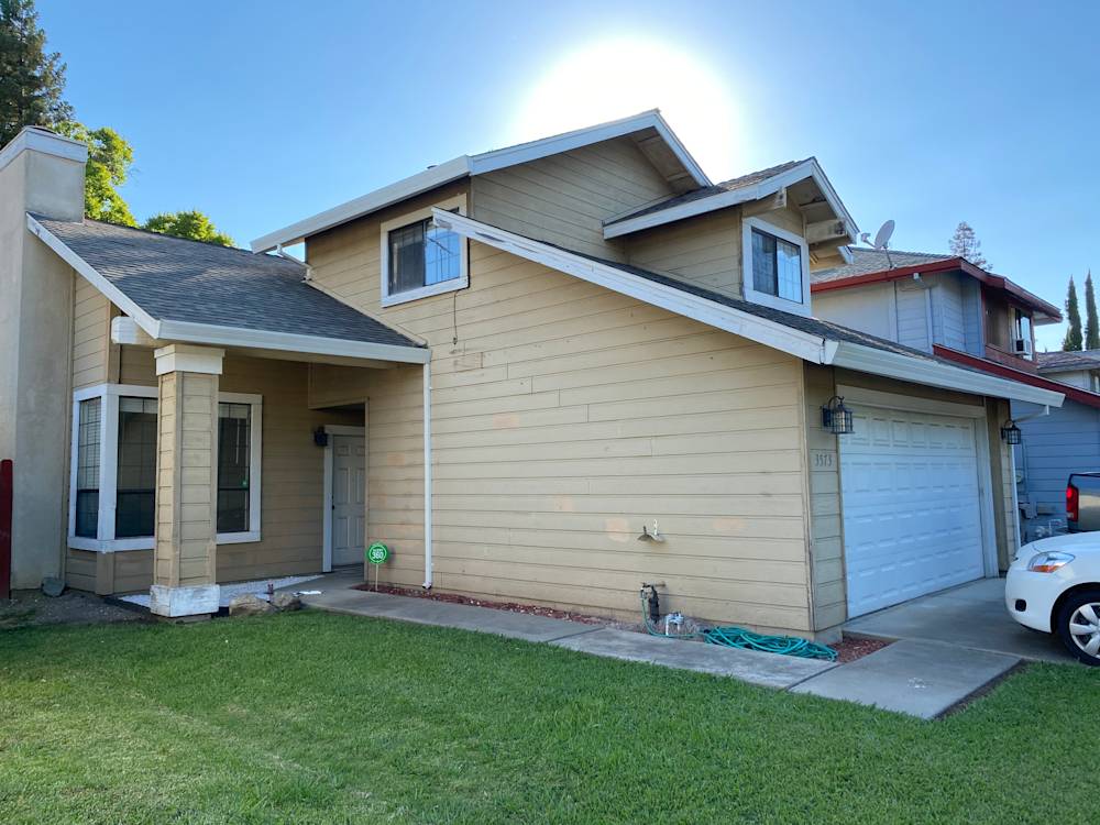 Outdated exterior of a two-story home in Sacramento, featuring beige siding and a garage