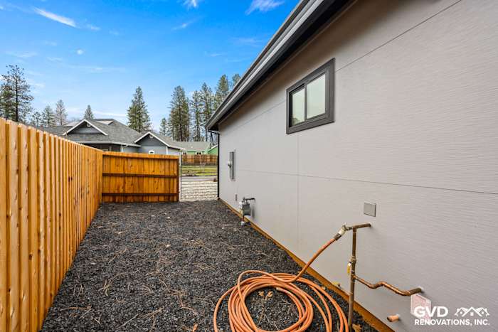 Side view of new home in Paradise, featuring James Hardie Architectural Panels and Milgard black windows, with a gravel