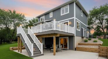 Stylish outdoor deck with white railing, seating area, and landscaped backyard, showcasing GVD Renovations craftsmanship