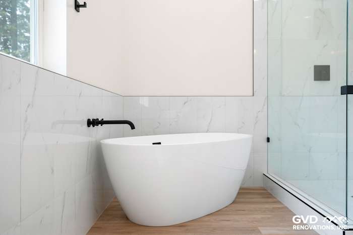 Modern bathroom featuring a freestanding white tub, marble wall tiles, and black fixtures in Paradise, CA