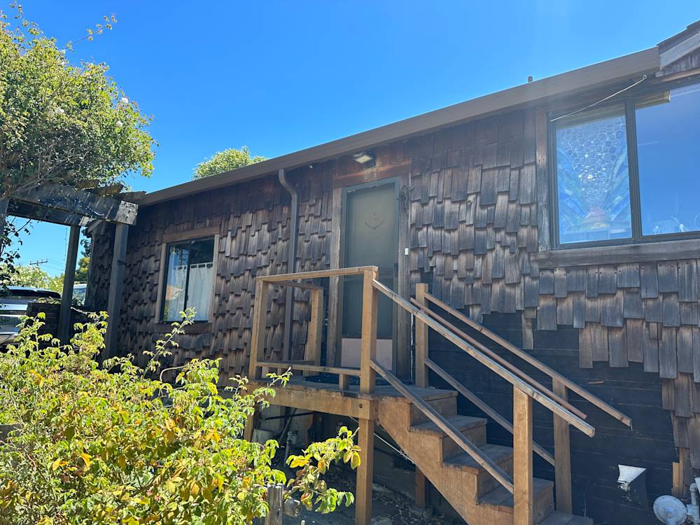 Wooden exterior with shingle design, dark paint, and stairs leading to front door in Sacramento