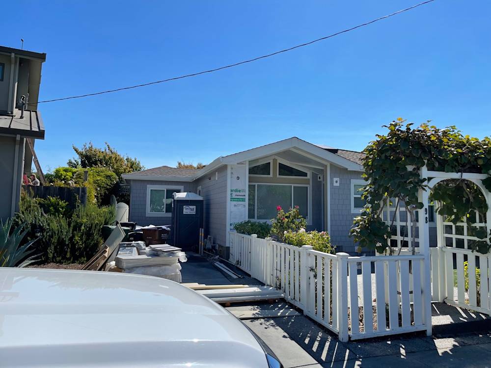 Gray single-story house with white fence and garden in Sacramento under clear blue sky