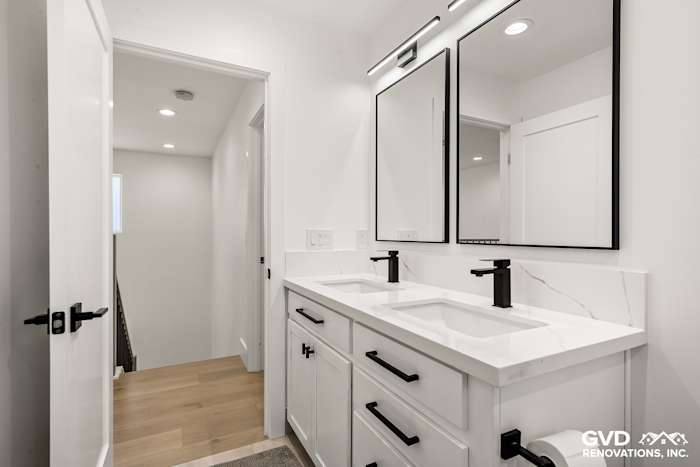 Modern bathroom remodel featuring a dual vanity with black faucets, marble countertops, and stylish mirrors in Antelope, CA