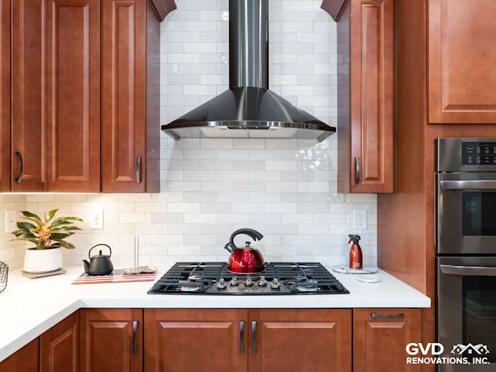 Spacious kitchen remodel with warm wood cabinetry, white subway tile, and stainless steel hood in Elk Grove