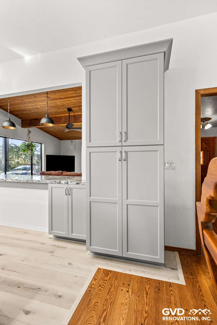 Modern kitchen remodel showing tall gray cabinetry, light wood flooring, and an open layout in Greenwood, CA