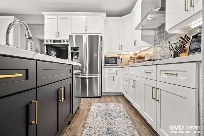 Modern kitchen remodel featuring white custom cabinets, black island, Cambria countertops, and stainless steel appliances