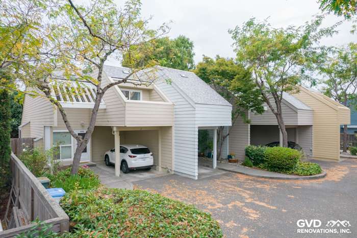 Quadplex exterior featuring newly installed James Hardie siding in soft beige, surrounded by landscaped greenery