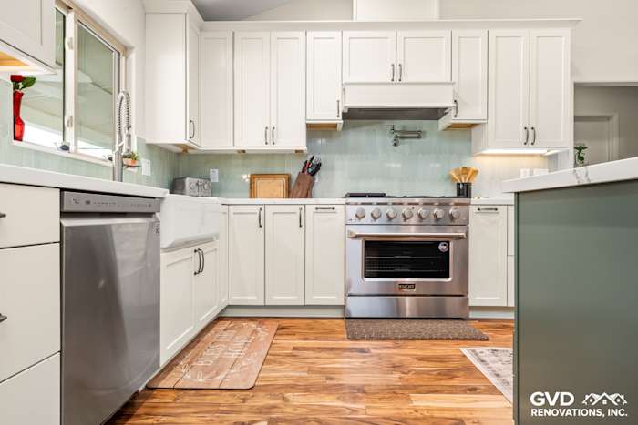 Modern kitchen in Carmichael with white cabinets, stainless steel appliances, and wood flooring. Features an elegant