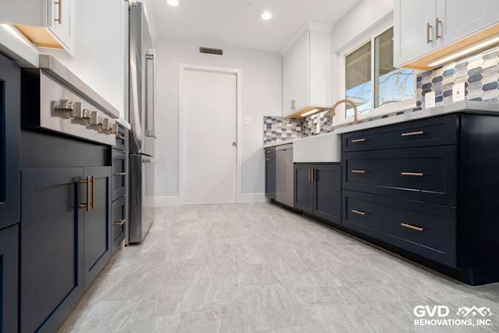 Modern kitchen remodel featuring navy blue cabinets, white quartz countertops, and geometric backsplash tile