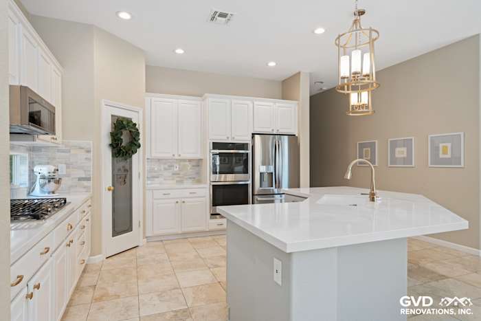 Bright, modern kitchen featuring white cabinets, quartz countertop, stainless steel appliances, and decorative backsplash
