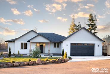 Custom-built home exterior in Paradise, CA featuring James Hardie board and batten siding, stone accents, and a modern garage
