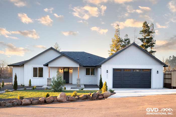Custom-built home exterior in Paradise, CA featuring James Hardie board and batten siding, stone accents, and a modern garage