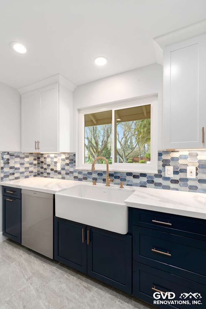Modern kitchen remodel featuring navy blue cabinets, a farmhouse sink, quartz countertops, and a stylish backsplash