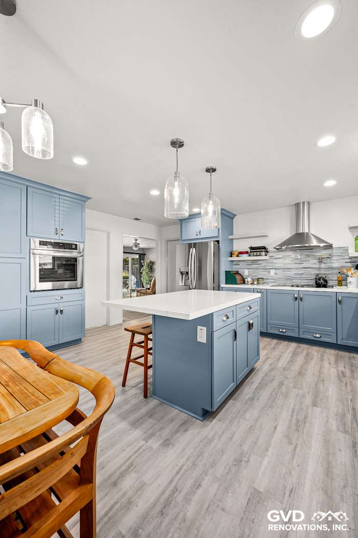 Modern kitchen remodel in Elk Grove with blue Waypoint cabinets, white island, and pendant lighting
