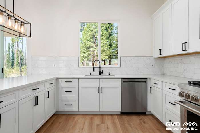 Bright custom kitchen featuring white cabinetry, marble backsplash, stainless steel appliances, and large windows