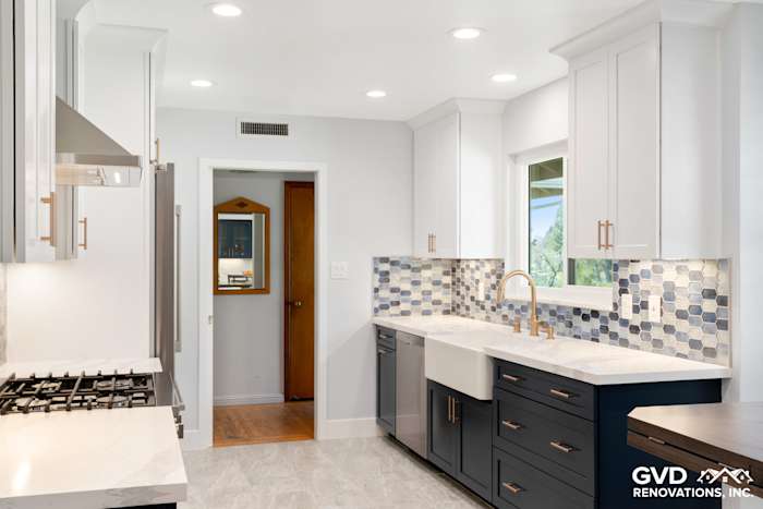 Modern kitchen with white cabinets, navy blue island, quartz countertops, and mosaic backsplash in Sacramento remodel