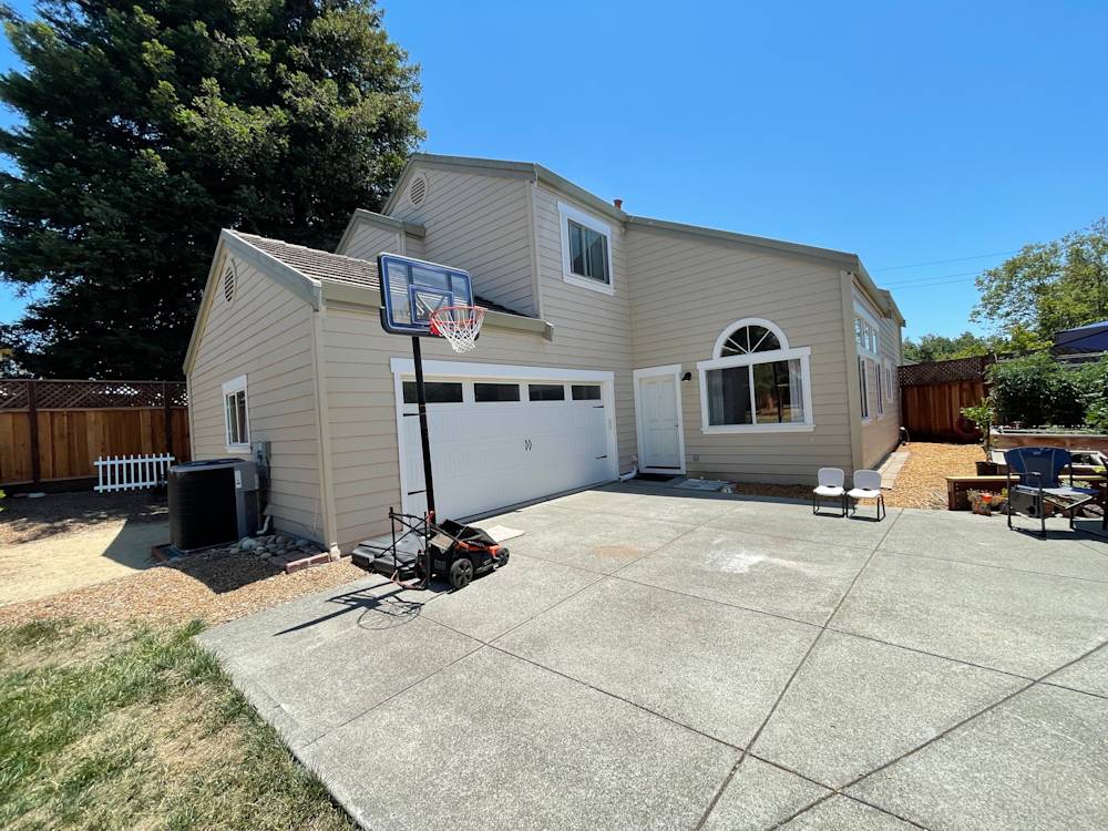 Spacious concrete driveway with basketball hoop and beige siding, located in Sacramento suburban setting
