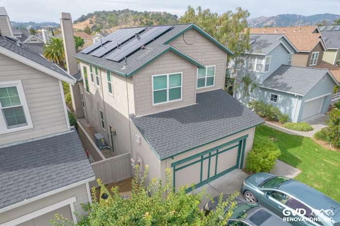 Two-story home in San Rafael featuring new Anlin Catalina windows, gray siding, and solar panels on the roof