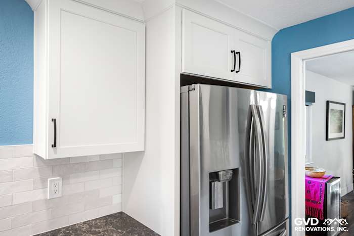 Modern kitchen corner featuring white cabinets, stainless steel refrigerator, and light gray backsplash in Fair Oaks