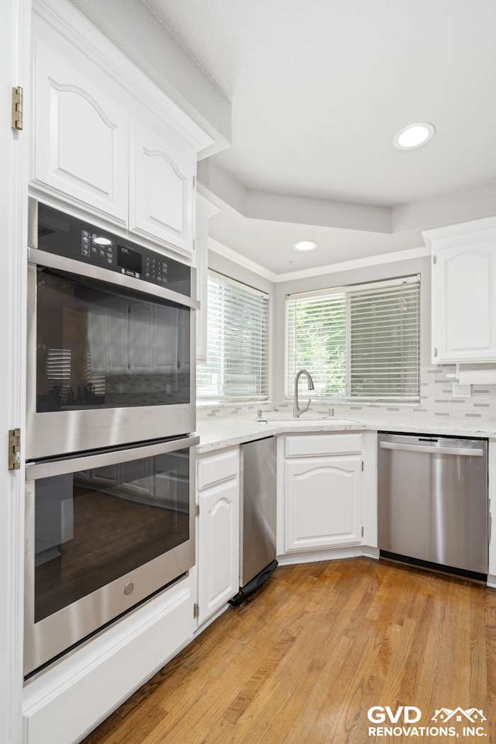 Modern kitchen renovation in Fair Oaks with white cabinetry, stainless steel appliances, and warm wooden flooring