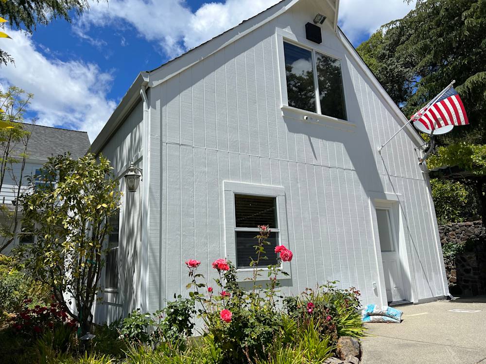 Charming white home exterior with roses, American flag, and lush greenery in Deer Park, Northern California